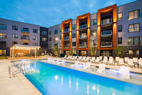 2 Bedroom Luxury Apartments in Berkley Riverfront, MO - Union Berkley - Resort-Style Pool with Spacious Sundeck, Submerged and Poolside Lounge Chairs, and View of Apartment Buildings.