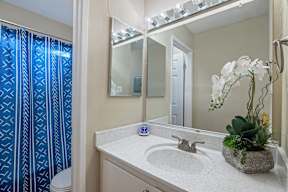 A bathroom with a sink, mirror, and a blue shower curtain.