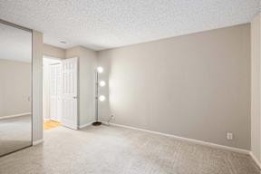 A room with a white door and a carpeted floor.