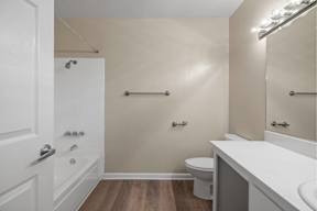 Santa Clara, CA, Affordable Apartments Near PayPal Park - Montecito Apartment Homes - Bathroom with a White Bathtub, Single-Sink Vanity, Large Window, Light Fixtures, and Towel Bars.