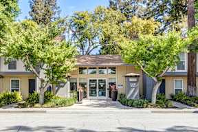 A building with a brown roof and a glass door is surrounded by green trees.