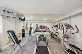 A gym with treadmills, exercise bikes and a television.