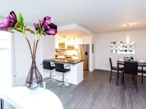 A dining room with a table set for two and a kitchen area in the background.
