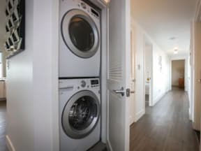 A white washing machine is in a narrow hallway.