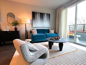 A modern living room with a blue sofa and a grey armchair.