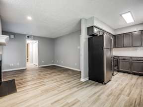 A kitchen with a black fridge and wooden floors.