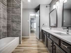 A bathroom with a tub, sink, and mirror.