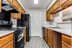 A kitchen with black appliances and wooden cabinets.