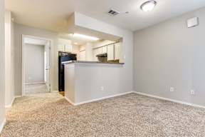 A spacious living room with a kitchenette in the background.