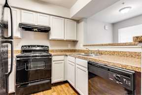 A black stove and oven in a kitchen with white cabinets.