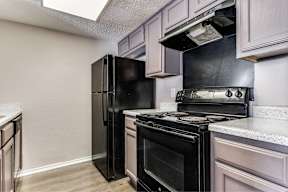 A black refrigerator and stove in a kitchen.