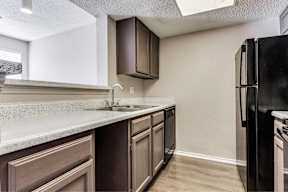 A kitchen with a black refrigerator and brown cabinets.