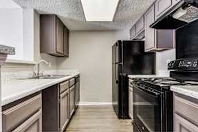 A kitchen with black appliances and brown cabinets.
