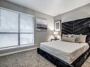 A bedroom with a large bed and a picture on the wall.