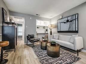 A living room with a white couch, a black chair, and a coffee table.
