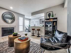 A black leather chair sits in a living room with a fireplace and a round mirror on the wall.