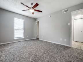 A room with a ceiling fan and carpeted floor.