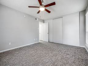 A room with a ceiling fan and carpeted floor.