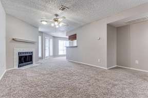 A spacious living room with a fireplace and carpeted floor.