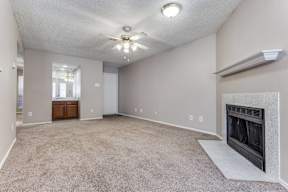 A spacious living room with a fireplace and a ceiling fan.