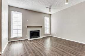 A spacious living room with a fireplace and wood flooring.