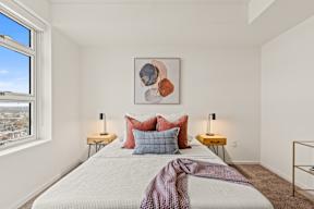 A bedroom with a large bed, two lamps, and a painting on the wall.