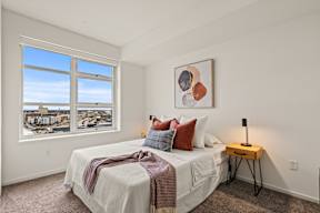 A bedroom with a large bed and a view of the city through the window.