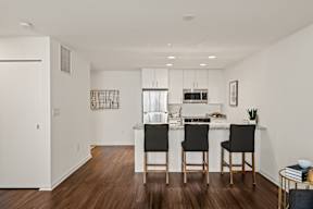 A kitchen with a white countertop and black chairs.