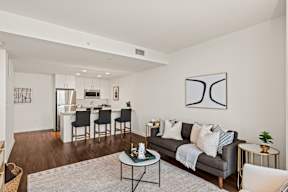 A modern living room with a grey couch, a coffee table, and a dining table with chairs.