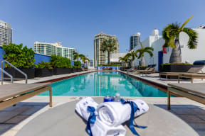 a swimming pool with palm trees and buildings in the background