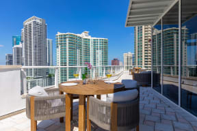 a patio with a table and chairs on a balcony overlooking the city
