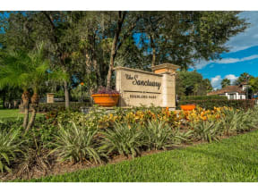 the condominium sign in front of plants and trees