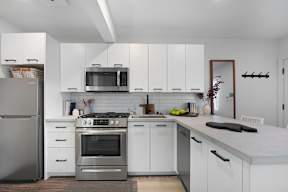 A modern kitchen with white cabinets and stainless steel appliances.