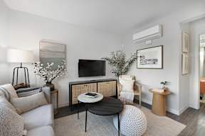A living room with a grey couch, a black table, and a television.