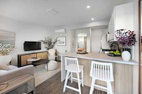 A modern kitchen with white chairs and a wooden counter.