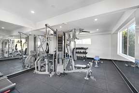 A well lit gym with a variety of equipment.