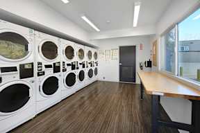 A laundromat with rows of washing machines and a bench.