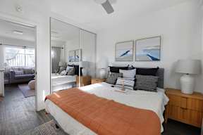 A bedroom with a large bed and a mirror on the wall.