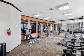 A gym with a variety of equipment including treadmills, weights, and exercise machines.