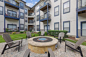 A patio with chairs and a fire pit in front of a building.