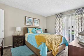 A bedroom with a bed covered in a blue and yellow comforter.