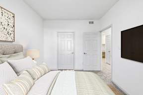 A bedroom with a bed, two doors, and a painting on the wall.