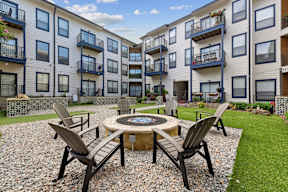 A patio with chairs and a table in front of apartment buildings.