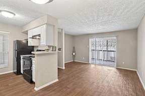 A kitchen area with a black fridge and white cabinets.