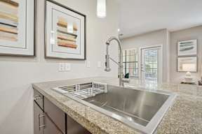 A modern kitchen with a granite countertop and stainless steel sink.