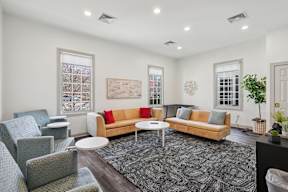 A living room with a couch, chairs, and a rug.