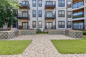 A modern apartment complex with a courtyard and a stone wall.