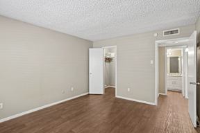 A room with a white door and a white cabinet with a mirror above it.