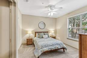A bedroom with a bed, nightstands, and a window.