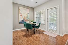 A dining room with a green table and chairs.